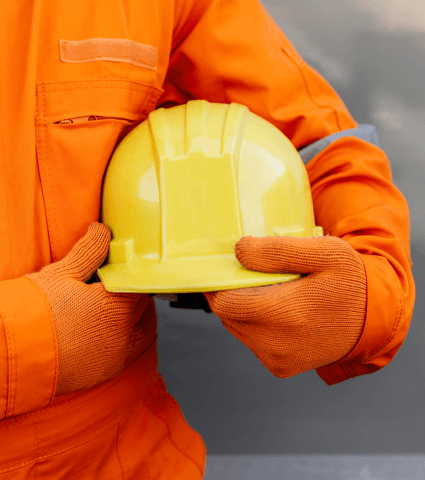 Мужчина в оранжевой униформе держит в руках каску