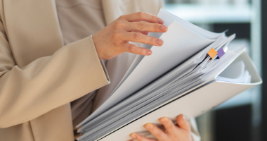 Женщина держит в руках стоку бумаг